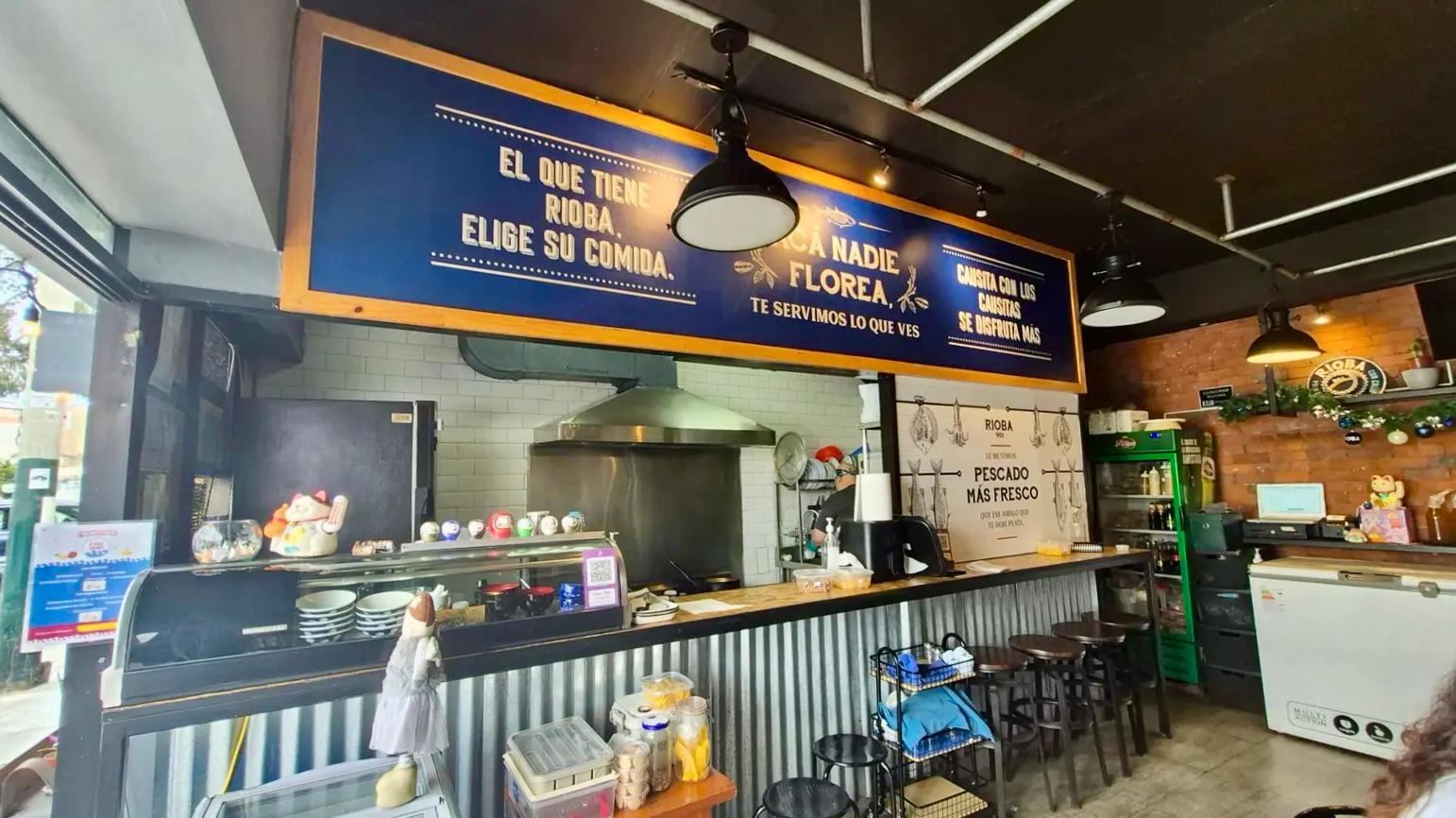 Interior view of Rioba 901 restaurant in Pueblo Libre with bar seating and kitchen workspace.